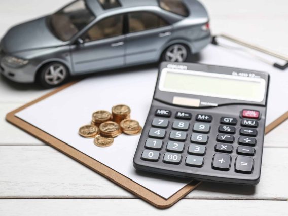 voiture miniature posée sur un bureau avec une calculatrice et des pièces